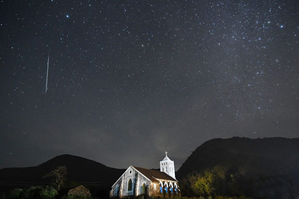 Une étoile filante des Géminides au-dessus d’une vieille église la nuit