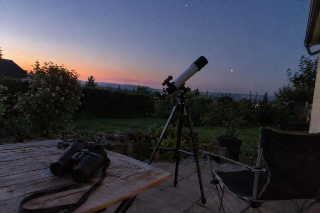 Jumelles et petite lunette astronomique sur une terrasse au crépuscule