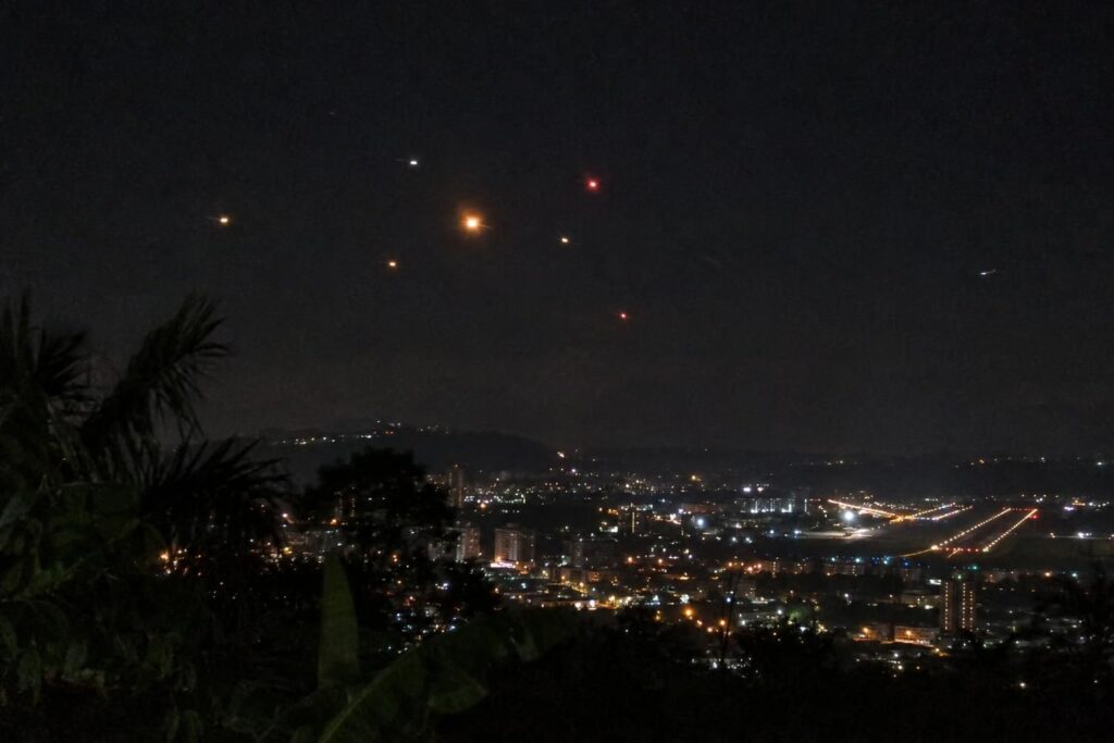 Illustration : groupe de lumières colorées dans le ciel nocturne au-dessus d’une ville brésilienne et de son aéroport