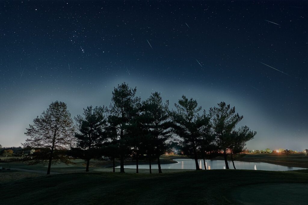 Composite de plusieurs météores des Orionides filant au-dessus d’un paysage nocturne