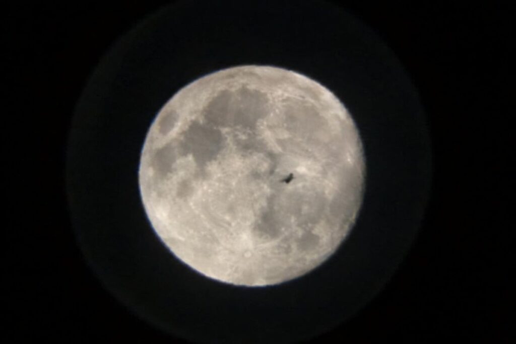 Silhouette sombre passant devant la pleine Lune, vue au télescope