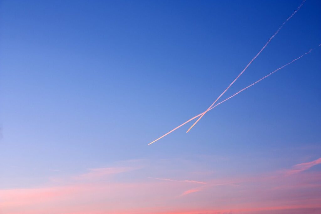 Traînées de condensation d’avions qui se croisent dans le ciel au coucher du soleil