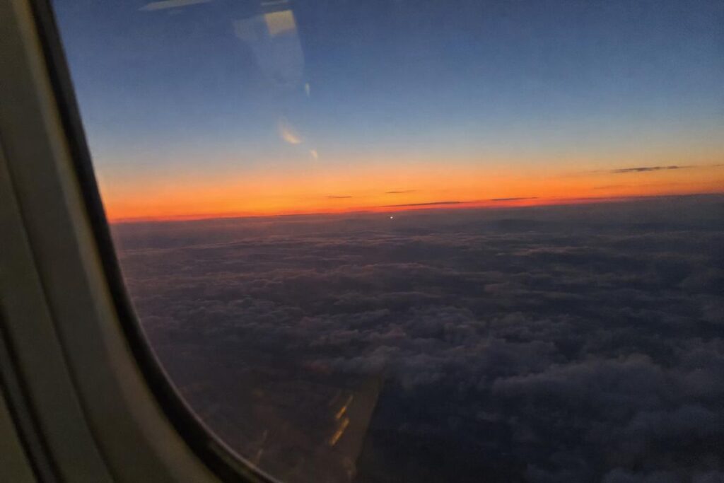 Lumière lointaine au-dessus des nuages au coucher du soleil, vue depuis un hublot