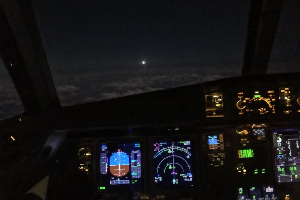 Lumière blanche au-dessus des nuages vue depuis un cockpit d’avion de ligne de nuit
