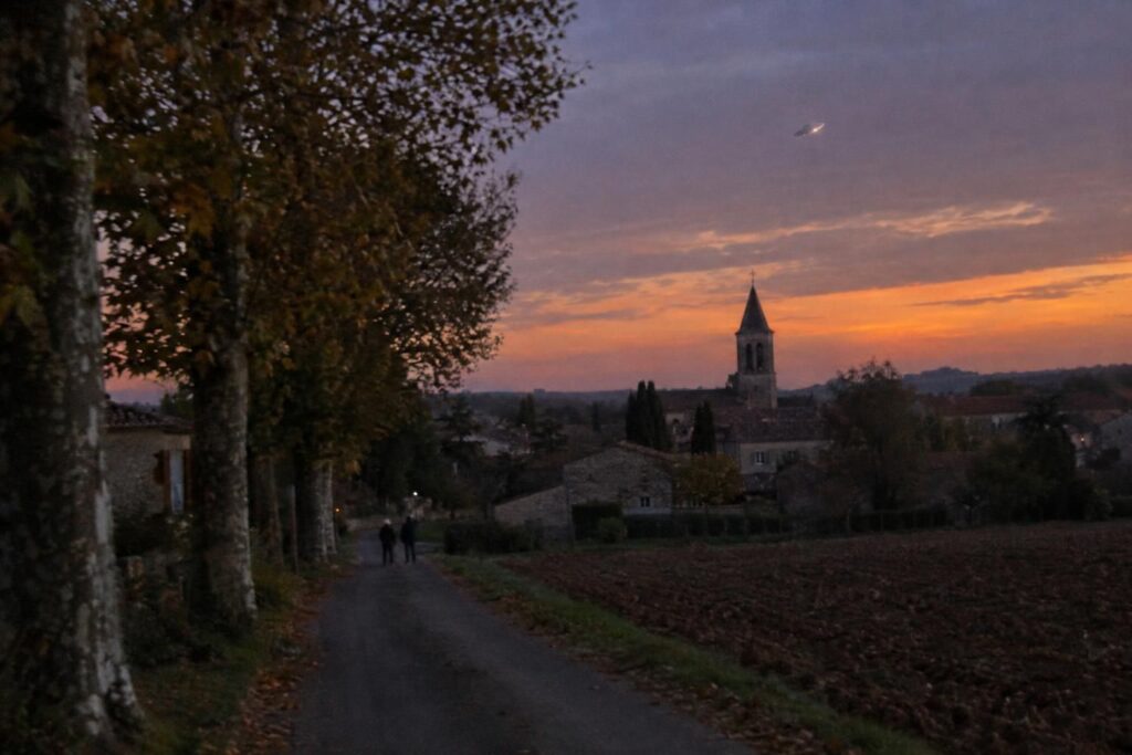 Illustration : petit disque métallique dans le ciel du crépuscule au-dessus d’un village français, en automne